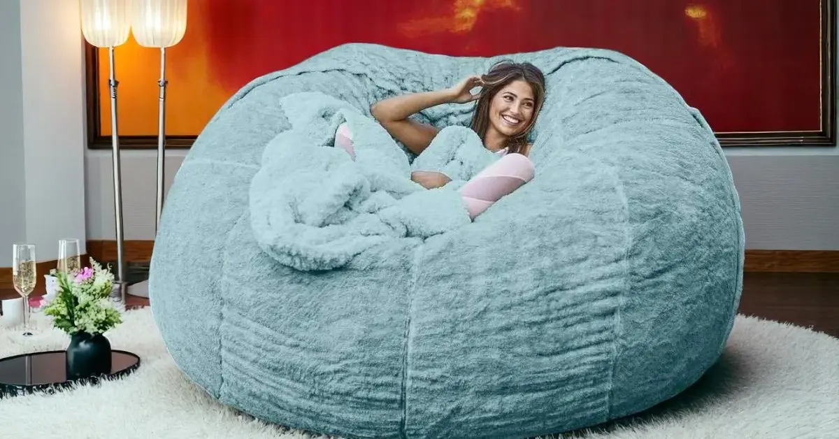 Soft and oversized grey bean bag bed in a cozy bedroom corner, designed for lounging, reading, or relaxing, with plush faux fur fabric and modern style.