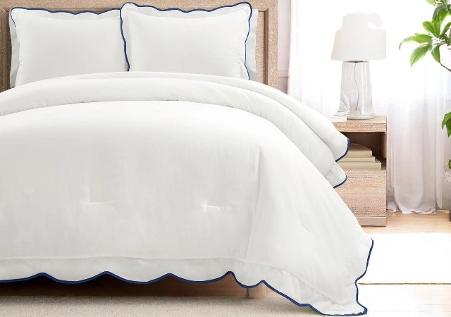 White and navy scallop edge comforter set on queen bed, featuring coastal design and soft cotton fabric with matching pillow shams