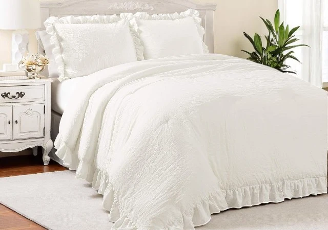 Lush Decor Reyna Ruffle Comforter Set in elegant white with ruffled edges, displayed on a king-sized bed in a shabby chic styled bedroom.