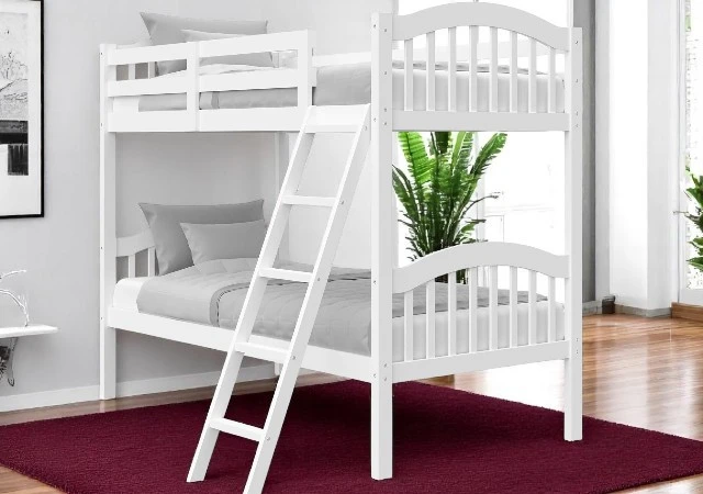 White Storkcraft Long Horn Twin-Over-Twin Bunk Bed with ladder and full-length guardrails, set in a cozy kids’ bedroom with matching decor.